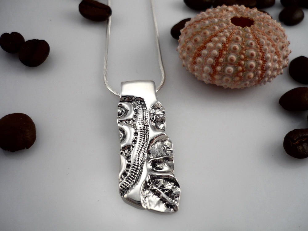 ELONGATED LAND AND SEA, sterling silver pendant with a sea urchin shell and coffee bean imprint!